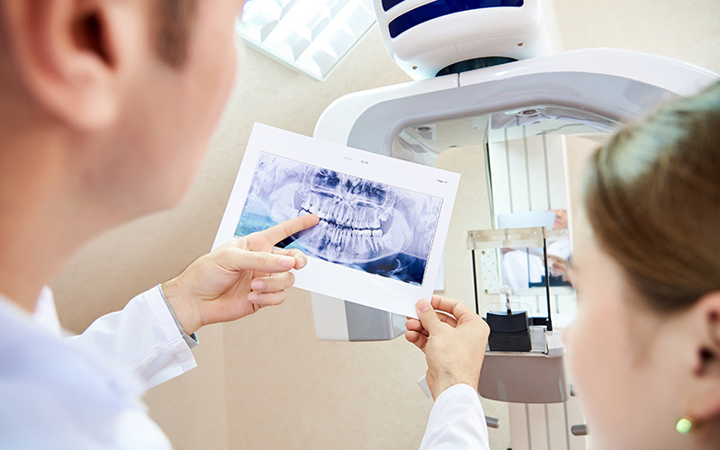 A dentist is showing a child an X-ray of their teeth on a monitor.